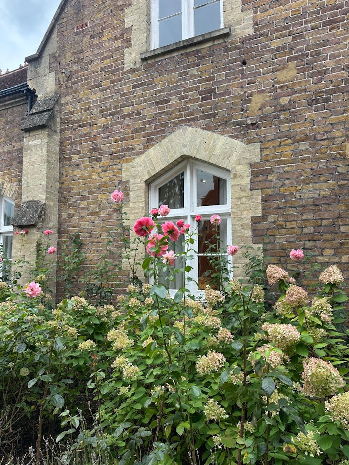 portfolio-04 Charming brick house facade with vibrant garden flowers in full bloom.