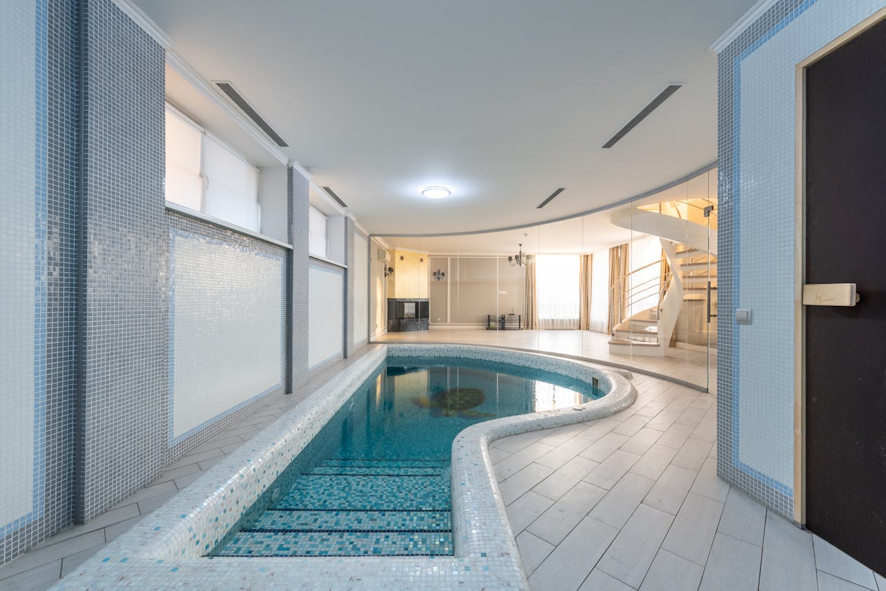 stats-img Serene indoor pool area with modern design and spiral staircase.