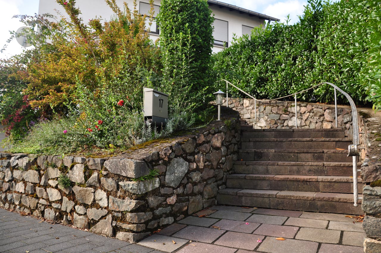 portfolio-03 Beautiful stone staircase surrounded by colorful bushes and greenery in an outdoor garden setting.